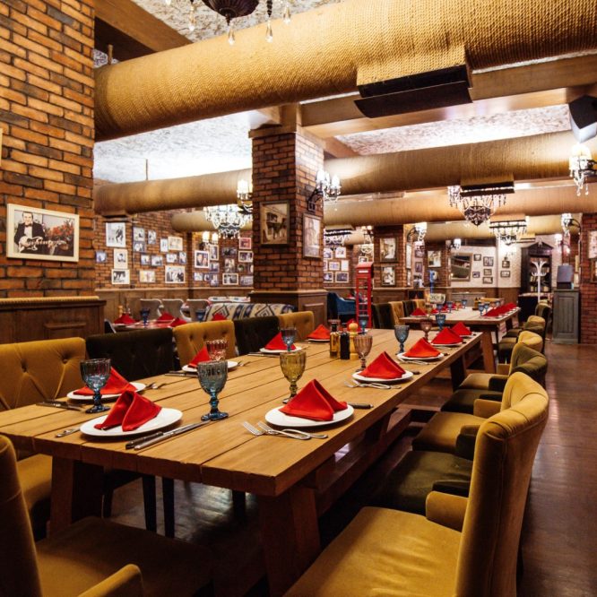 a restaurant hall with red brick walls wooden tables and pipes in the ceiling a restaurant hall with red brick walls wooden tables and pipes in the ceiling